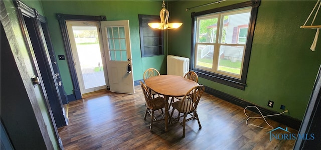 dining room with dark hardwood / wood-style flooring, radiator heating unit, and an inviting chandelier