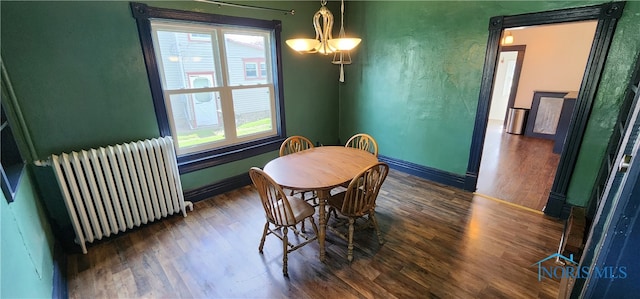 dining room with a notable chandelier, dark hardwood / wood-style floors, and radiator