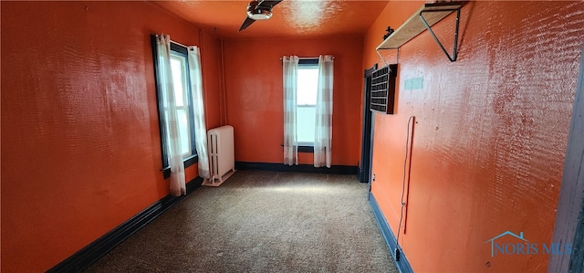 hallway featuring dark carpet and radiator