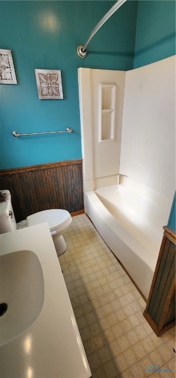 full bathroom featuring shower / bathing tub combination, toilet, sink, and wooden walls