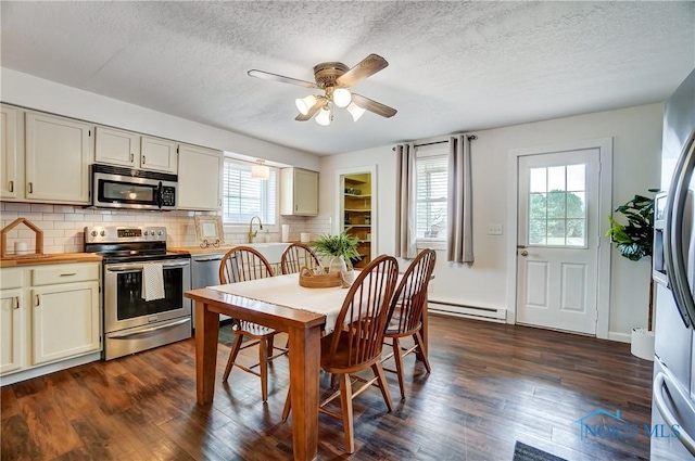 kitchen with stainless steel appliances, ceiling fan, dark hardwood / wood-style flooring, and baseboard heating