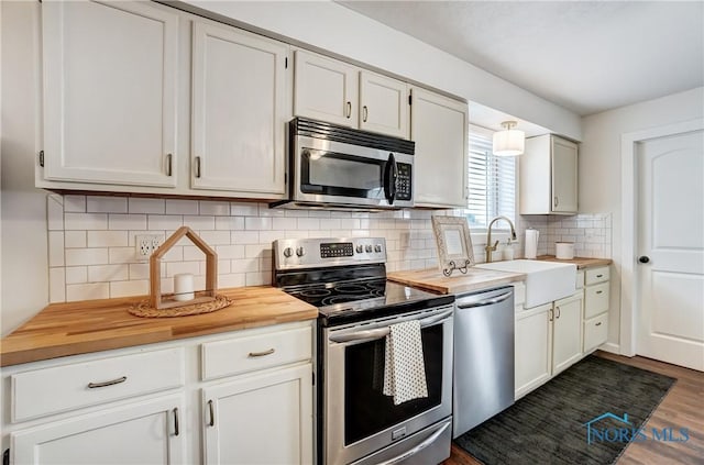 kitchen featuring appliances with stainless steel finishes, white cabinetry, butcher block countertops, and sink