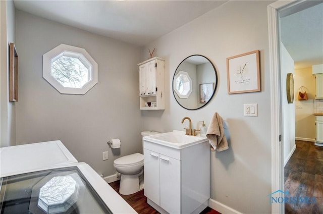 bathroom with toilet, vanity, washer and dryer, and hardwood / wood-style flooring