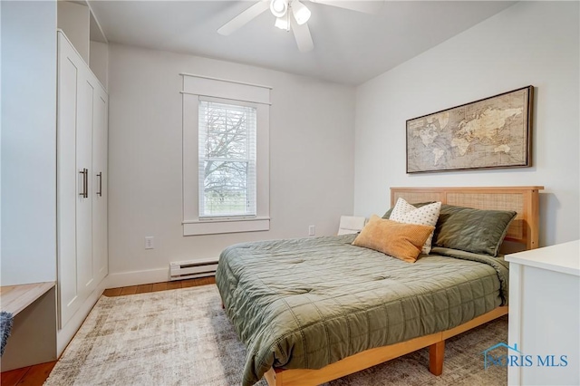 bedroom featuring baseboard heating, ceiling fan, and light wood-type flooring