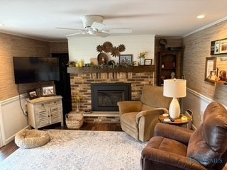 living room with ceiling fan, ornamental molding, wood-type flooring, and a brick fireplace