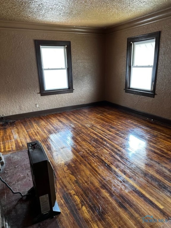 spare room featuring a textured ceiling, dark hardwood / wood-style flooring, and crown molding