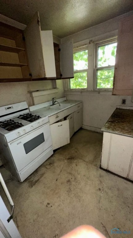 kitchen featuring white cabinetry, white range with gas stovetop, and sink