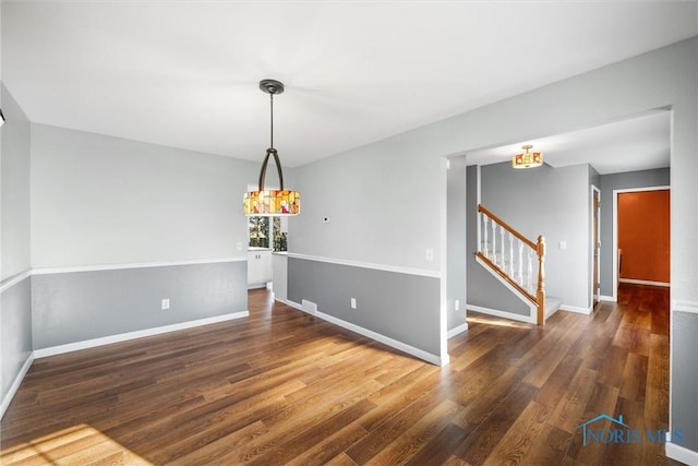 spare room with dark hardwood / wood-style flooring and a chandelier