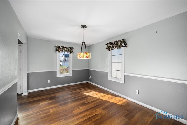 unfurnished dining area with dark wood-type flooring