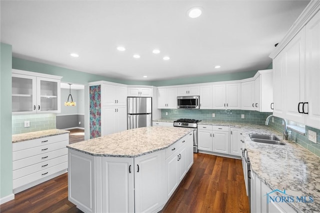 kitchen with sink, stainless steel appliances, dark hardwood / wood-style floors, decorative light fixtures, and white cabinets