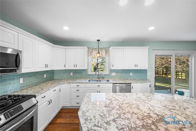 kitchen with sink, dark wood-type flooring, hanging light fixtures, white cabinets, and appliances with stainless steel finishes