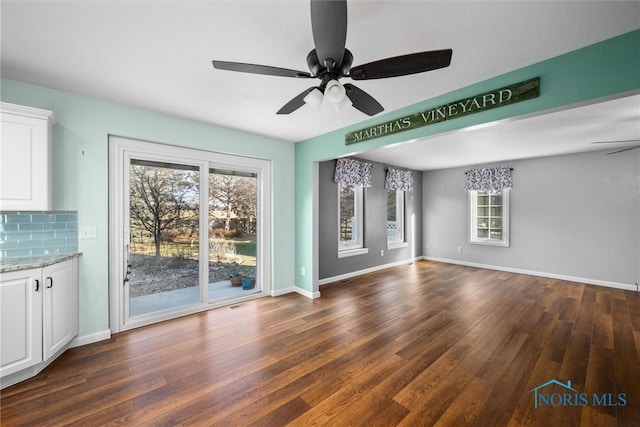 unfurnished living room with plenty of natural light, dark wood-type flooring, and ceiling fan