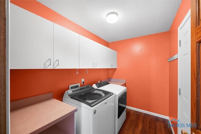 washroom with washing machine and clothes dryer, a textured ceiling, cabinets, and dark hardwood / wood-style floors