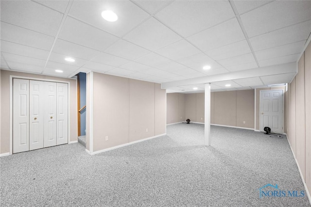 basement with a drop ceiling and carpet