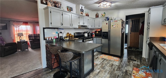 kitchen featuring a kitchen breakfast bar, crown molding, dark hardwood / wood-style floors, a textured ceiling, and stainless steel appliances