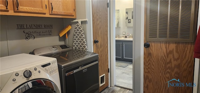 laundry area featuring cabinets, wood-type flooring, and washer and clothes dryer