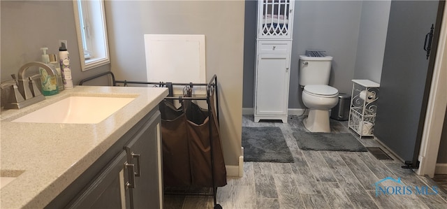 bathroom with vanity, toilet, and wood-type flooring