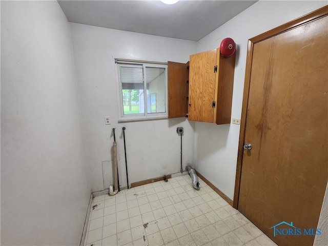 clothes washing area featuring electric dryer hookup and cabinets