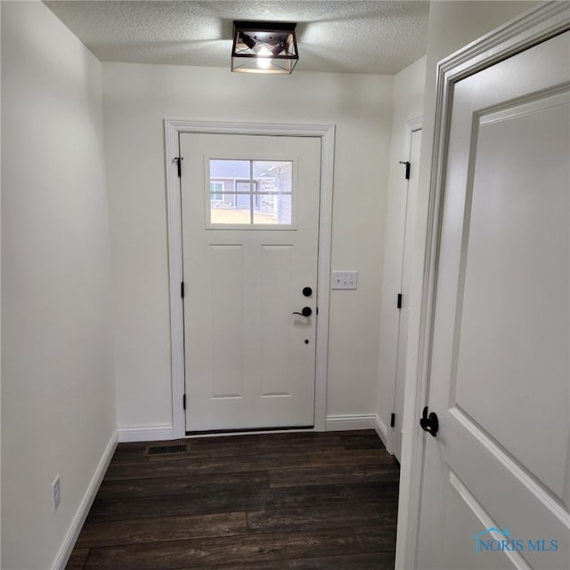 doorway featuring a textured ceiling and dark hardwood / wood-style floors