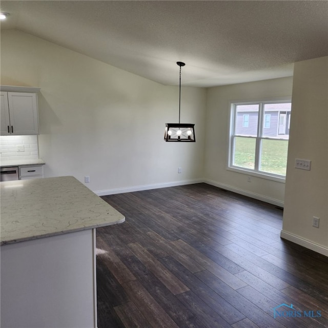 unfurnished dining area featuring a textured ceiling, lofted ceiling, and dark wood-type flooring