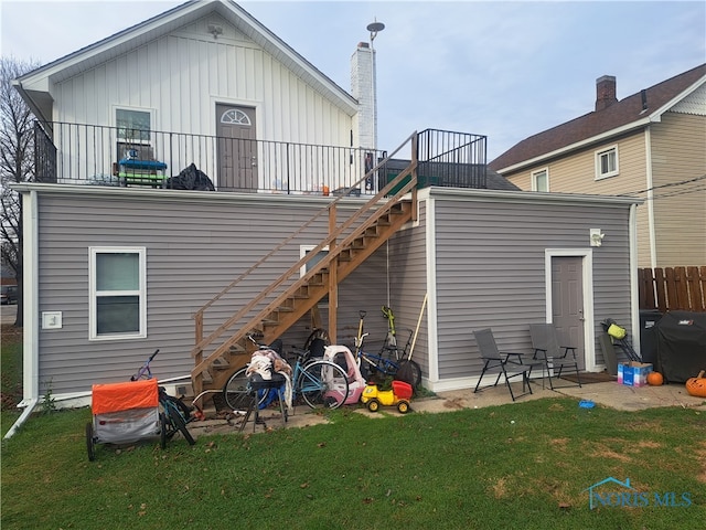 back of house with a lawn and a balcony