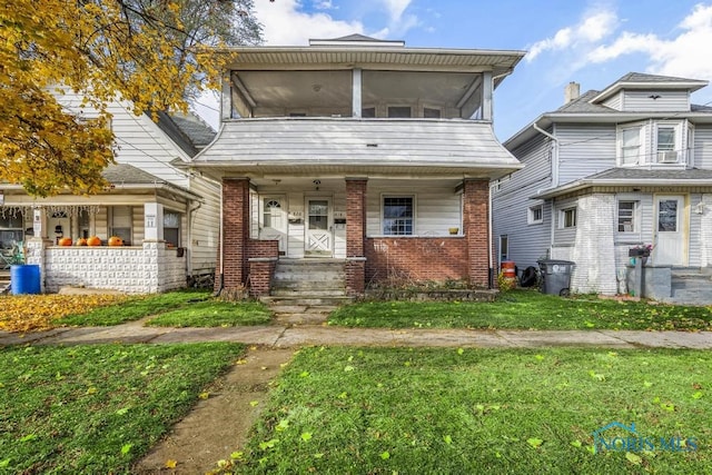 view of front of house with a sunroom and a front yard