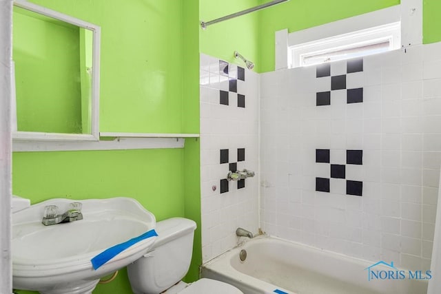 full bathroom featuring tiled shower / bath combo, toilet, and sink