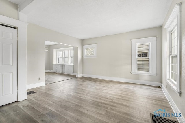 unfurnished room featuring light wood-type flooring and a textured ceiling