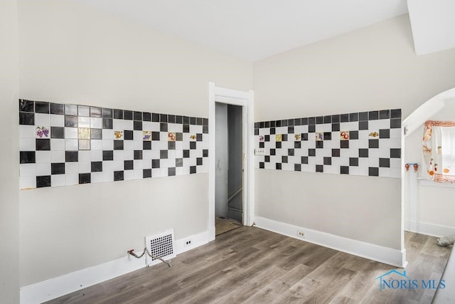 empty room with wood-type flooring and tile walls