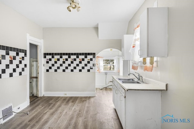 kitchen with white cabinetry, sink, and light hardwood / wood-style flooring