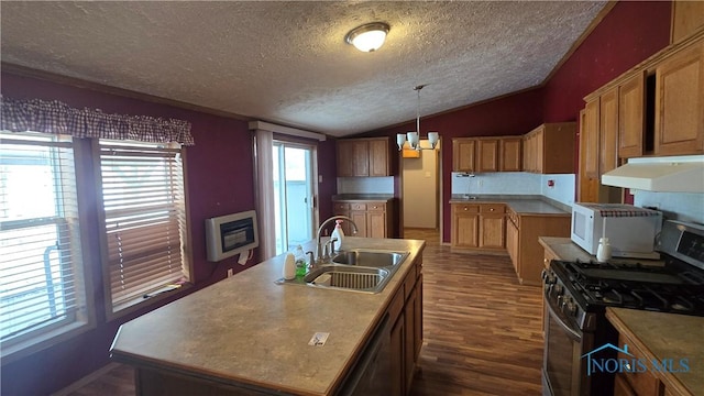 kitchen featuring gas range, sink, heating unit, an island with sink, and decorative light fixtures