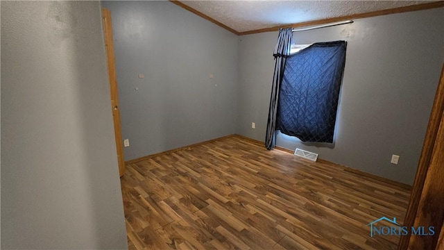 spare room featuring hardwood / wood-style floors, a textured ceiling, and crown molding