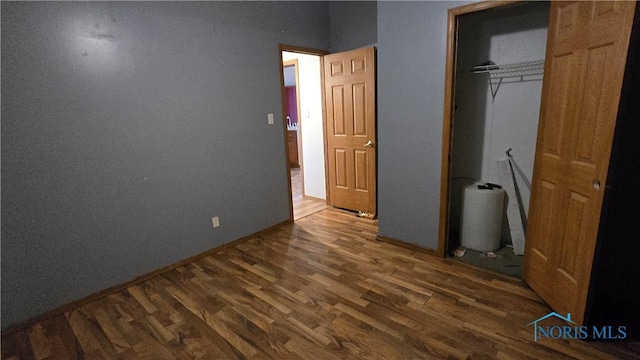 unfurnished bedroom featuring a closet and dark wood-type flooring