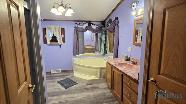 bathroom with vanity, hardwood / wood-style flooring, ornamental molding, a tub to relax in, and a chandelier