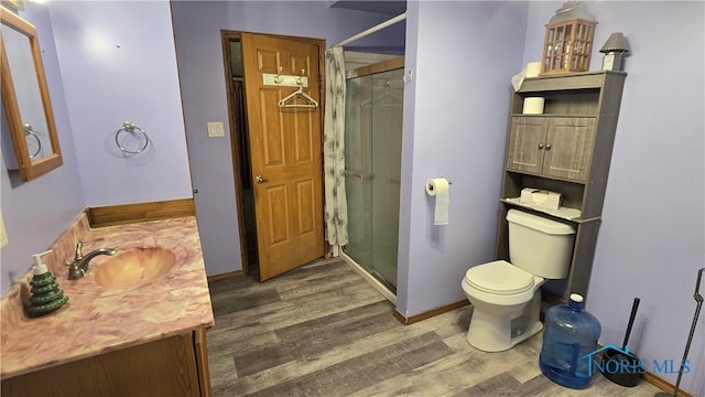 bathroom with hardwood / wood-style flooring, vanity, toilet, and an enclosed shower