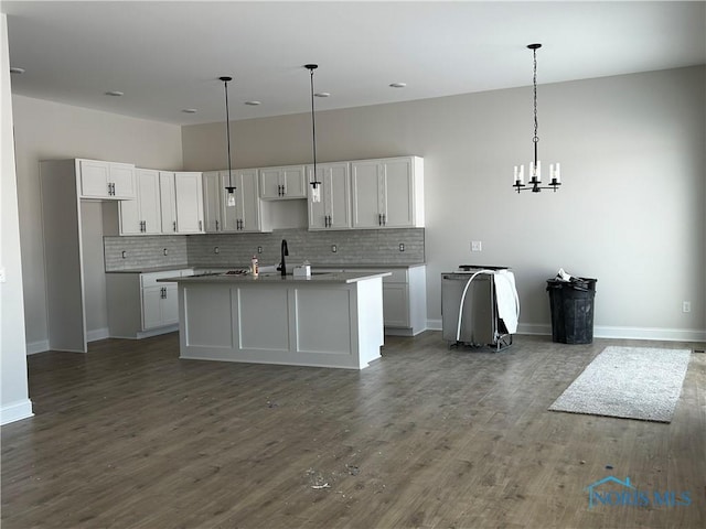 kitchen with decorative light fixtures, sink, a center island with sink, and white cabinets