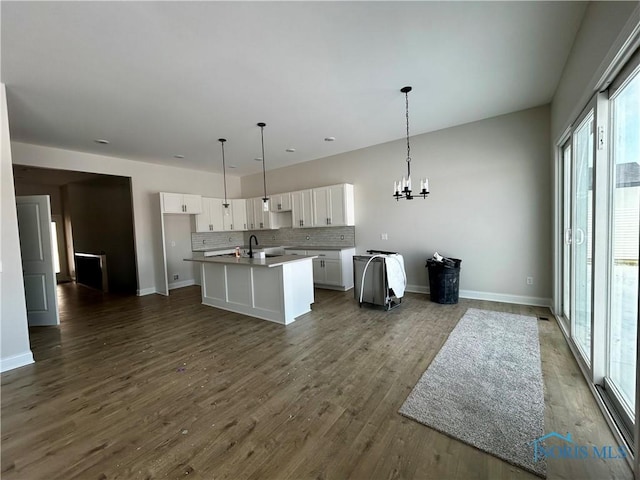 kitchen with an island with sink, sink, white cabinets, and decorative light fixtures