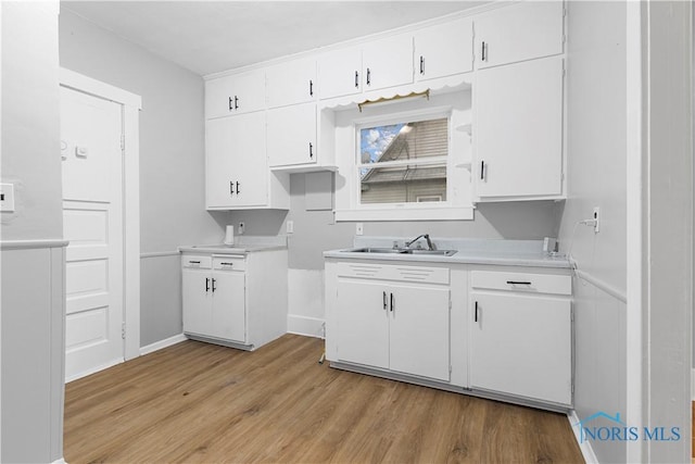 kitchen with white cabinets, light hardwood / wood-style floors, and sink