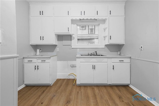 kitchen with light hardwood / wood-style flooring, white cabinetry, and sink