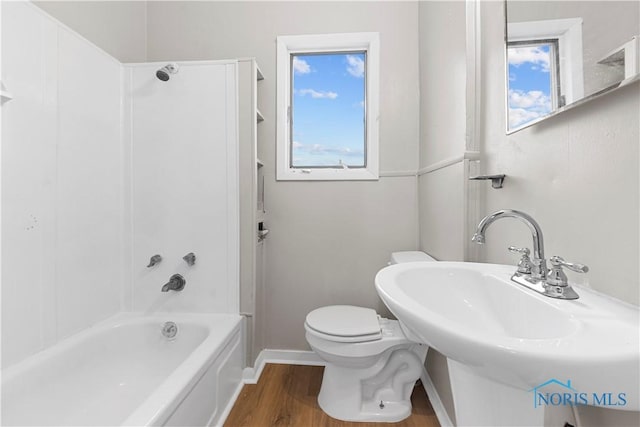 full bathroom with a wealth of natural light, toilet, shower / bathing tub combination, and hardwood / wood-style flooring