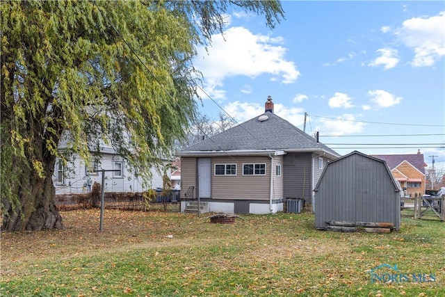 rear view of house with central AC unit, a shed, and a yard