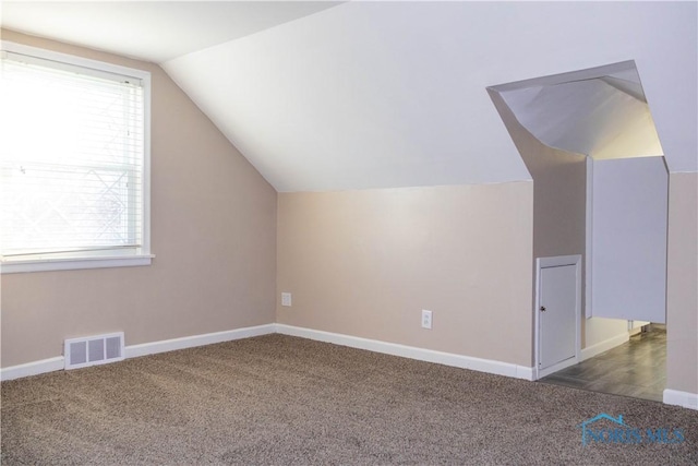 bonus room featuring dark colored carpet and vaulted ceiling