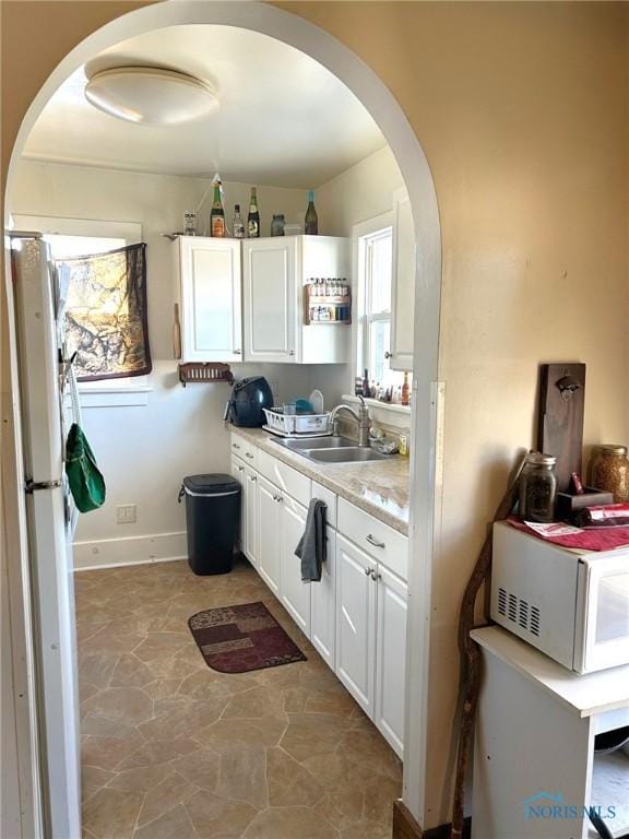 kitchen with white cabinets, white fridge, and sink