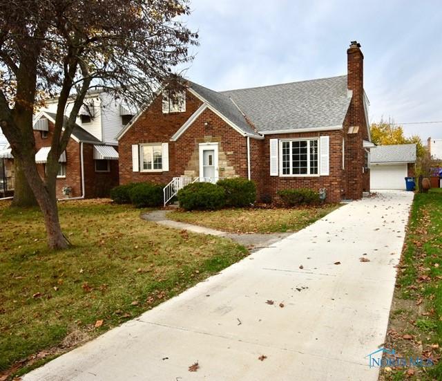 bungalow-style house featuring a garage, an outdoor structure, and a front yard