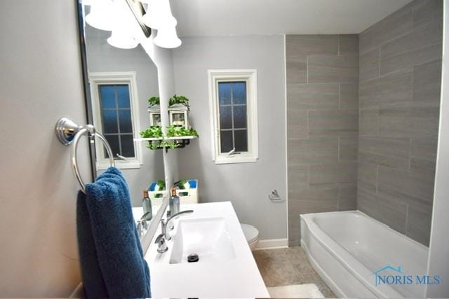 full bathroom featuring tiled shower / bath combo, toilet, and sink