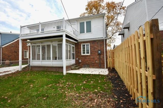 back of property featuring a lawn, a patio area, a sunroom, and a balcony