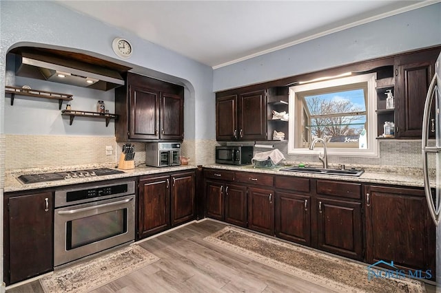 kitchen featuring stainless steel appliances, light hardwood / wood-style flooring, tasteful backsplash, and sink