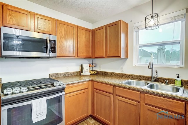 kitchen with sink, pendant lighting, a textured ceiling, and appliances with stainless steel finishes