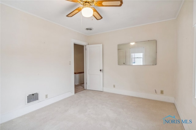 unfurnished room featuring ceiling fan, light colored carpet, and crown molding