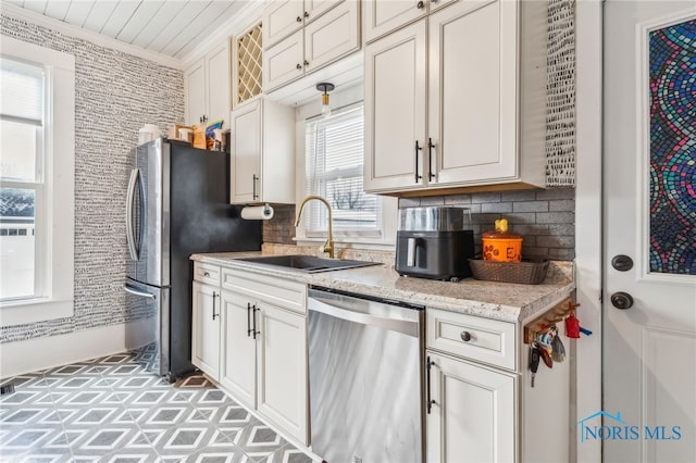 kitchen featuring sink, light stone countertops, ornamental molding, appliances with stainless steel finishes, and tasteful backsplash